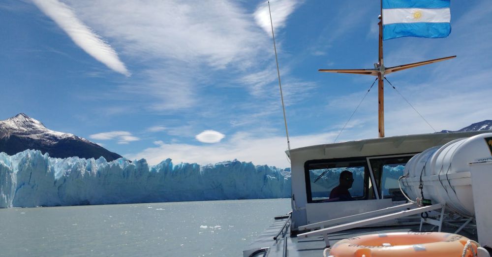 Glacier Tour Tips - View of the stunning Perito Moreno Glacier and a boat with the Argentine flag in El Calafate.