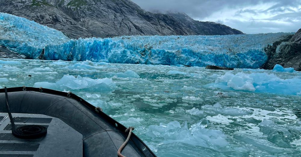 Boat Glacier Tours - Dramatic view of an inflatable boat navigating icy waters near polar icebergs.