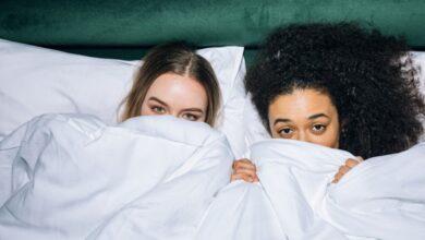 Best Time - Two young women having fun and relaxing under white bedding, illustrating friendship and comfort.