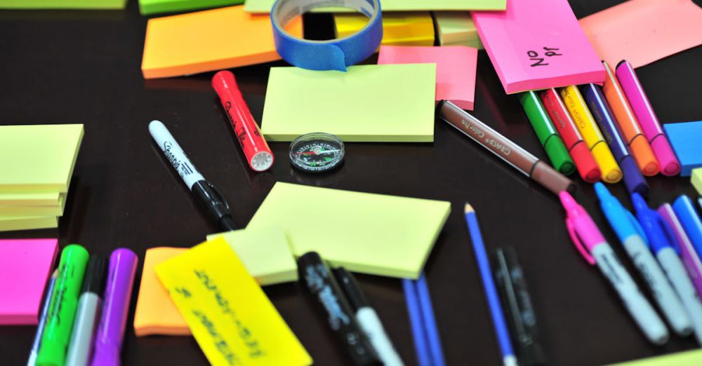 Stationery - Colorful assortment of office supplies on a desk, including sticky notes, pens, and markers.