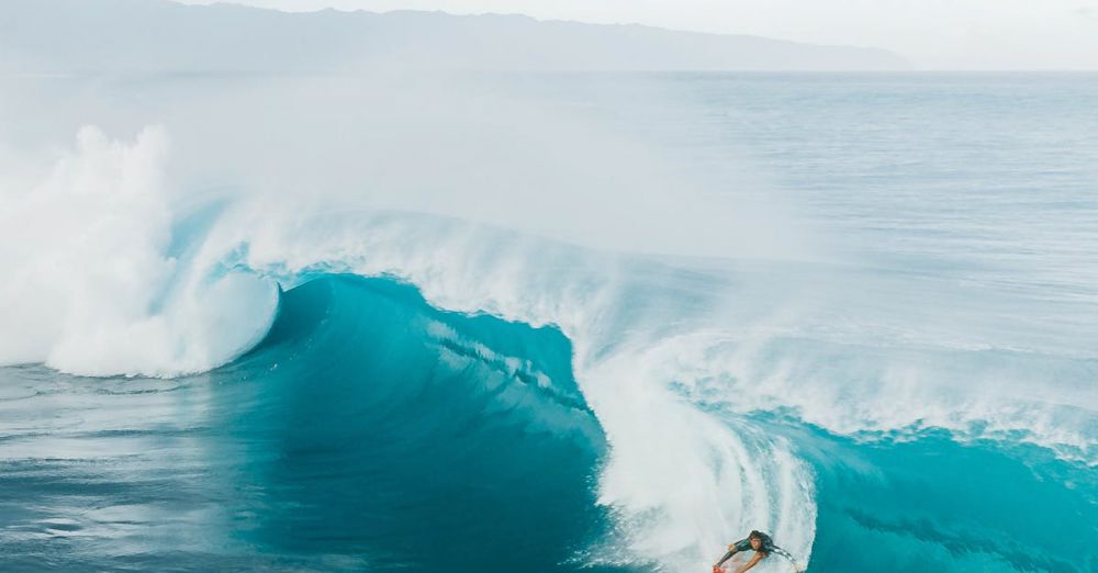 Big Waves - A surfer skillfully rides a large wave at Haleiwa Beach in Oahu, capturing the essence of adventure and excitement.