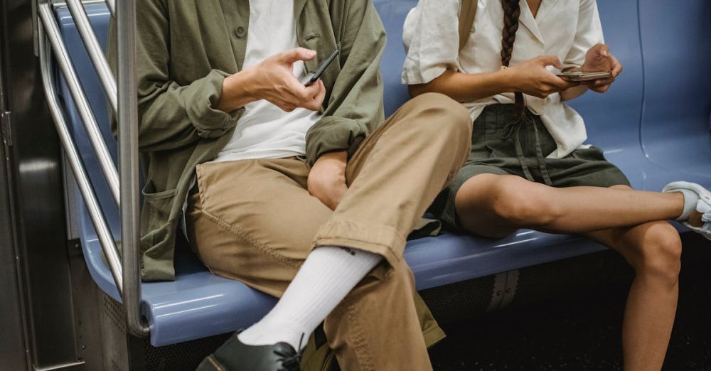 Surfing Safety - Two young adults with masks using smartphones on a subway ride.