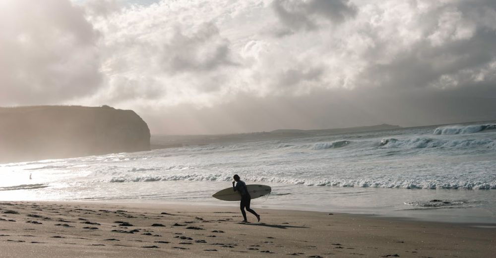 Surfing In Wind - A surfer walks on the beach with a surfboard