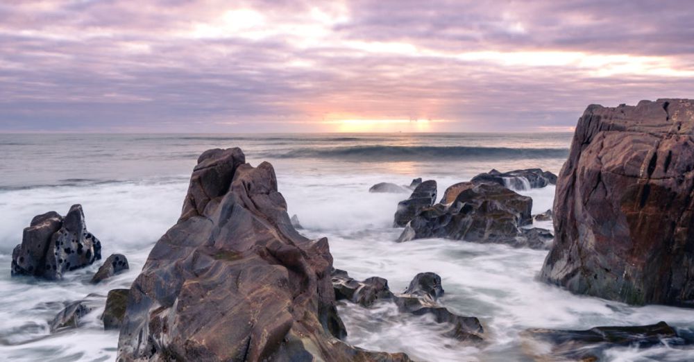 Nova Scotia Surfing - Dramatic sunset over rocky seashore in Vila Nova de Gaia, capturing vibrant and moody ocean scenery.