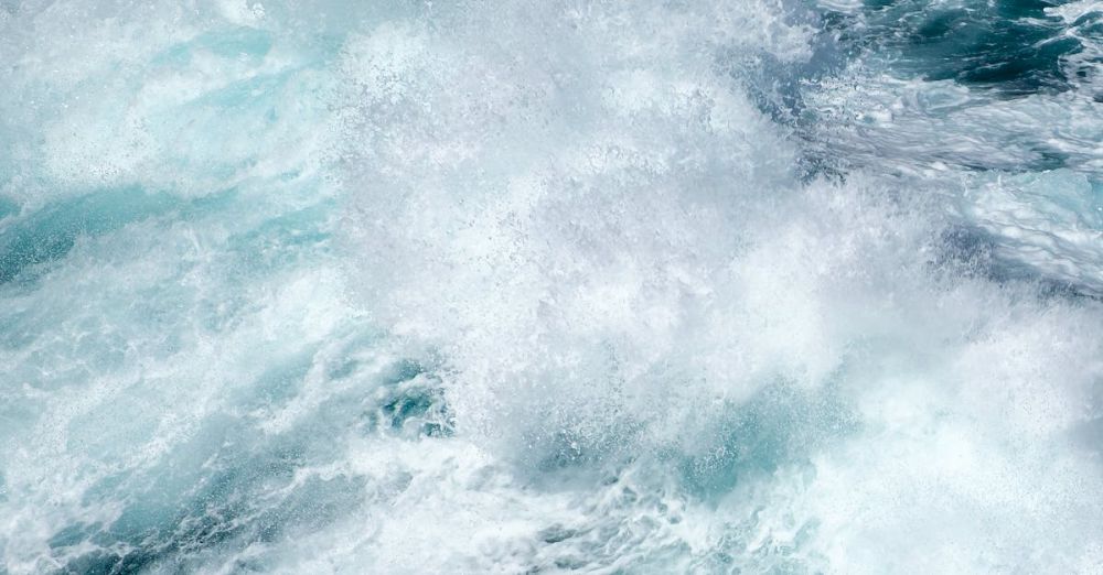 Surfing Conditions - A captivating high-angle view of a powerful ocean wave crashing and creating sea foam.