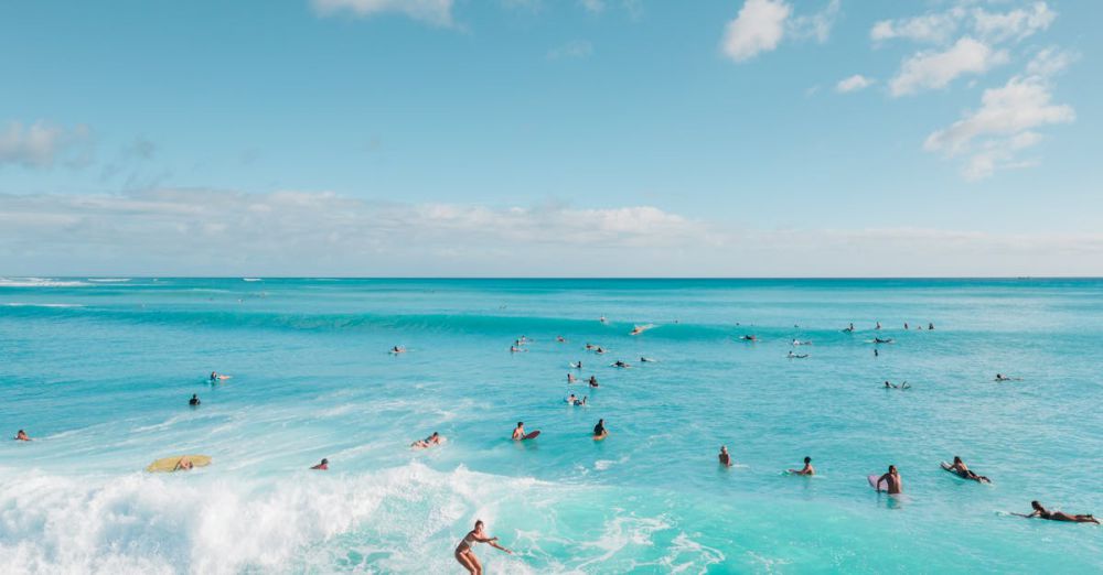 Surfing Lessons - A vibrant aerial photo capturing surfers enjoying waves in clear turquoise waters under a bright sky.