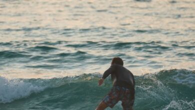 Sunset Surfing - A surfer skillfully rides a wave during sunset, showcasing the thrill of ocean adventure.