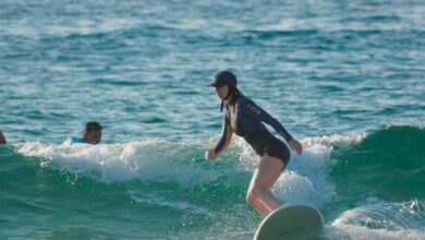 Scenic Surfing - A surfer skillfully rides a wave at a serene beach, showcasing balance and surfing technique.