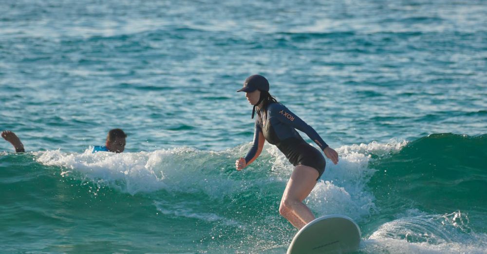 Scenic Surfing - A surfer skillfully rides a wave at a serene beach, showcasing balance and surfing technique.