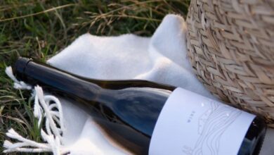 Weekend Getaways - Serene outdoor scene with wicker basket, wine bottle, and blanket on grassy field.