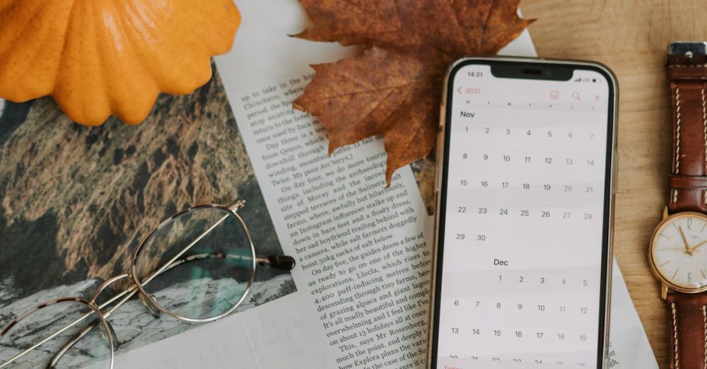 Fall Viewing Time - Cozy autumn flat lay with pumpkin, leaf, and smartphone displaying calendar.