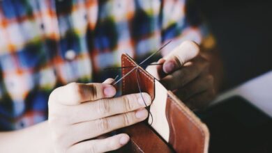 Leather Wallet - Close-up of a person hand-stitching leather, showcasing detailed craftsmanship and DIY skills.