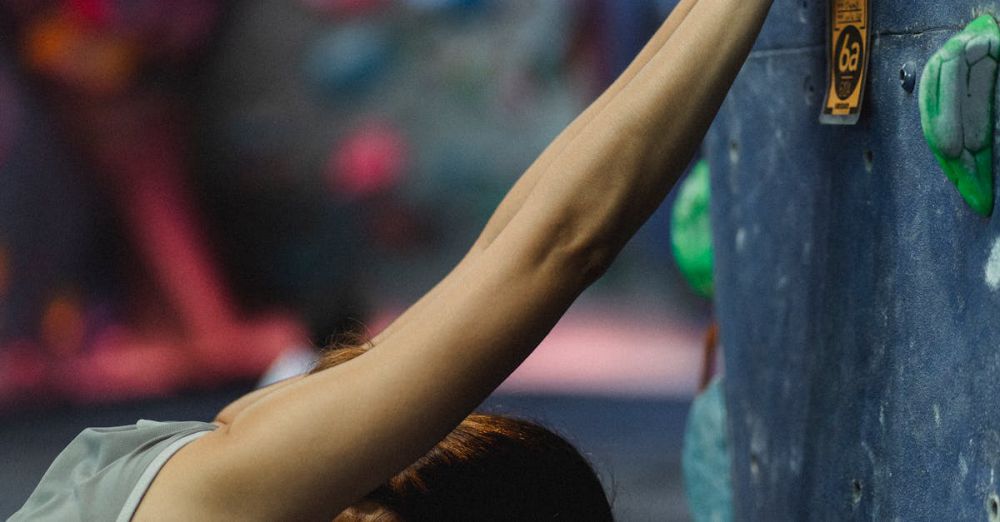 Climbing Preparation - A female climber stretches on an indoor climbing wall, preparing for a workout.