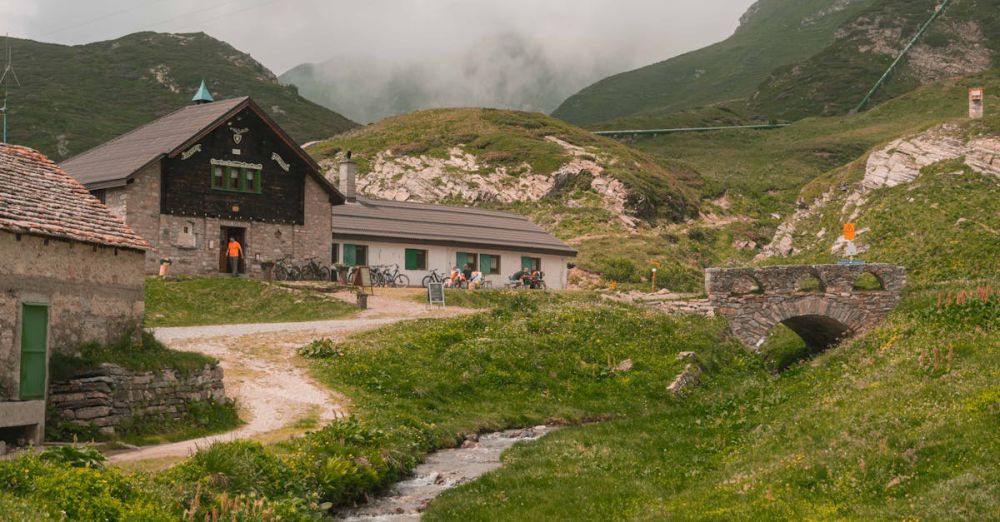 Scenic Trails - Tranquil mountain landscape with rustic cabins and lush greenery in Piemonte, Italy.