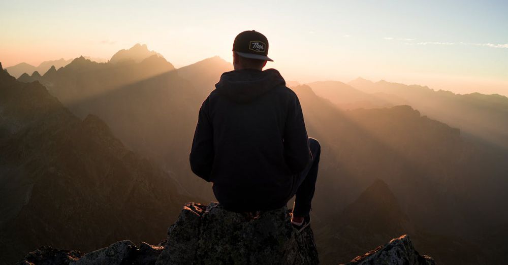 Top Peaks - A man sits on a peak in the High Tatras, Slovakia, enjoying a serene sunset view over the mountains.