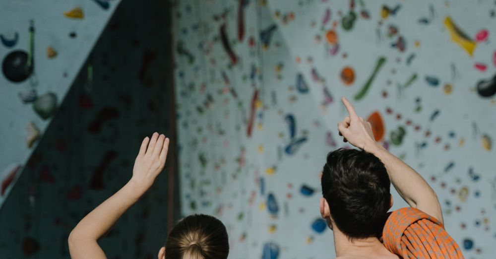 Climbing Skills - A man and woman engage in indoor rock climbing, preparing to scale a colorful wall.