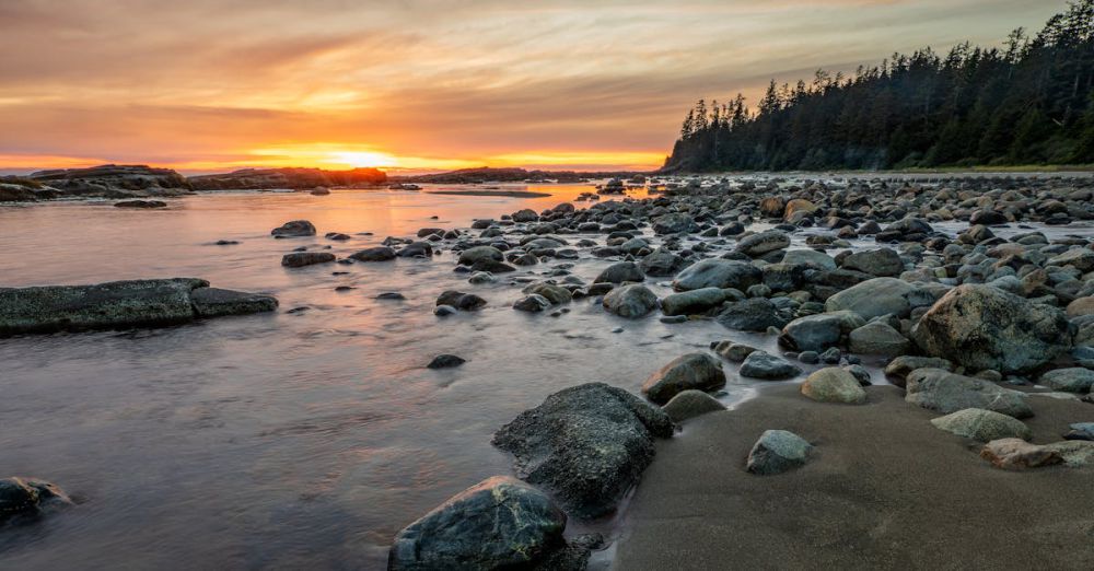 BC Trails - Beautiful sunset over a rocky beach in Vancouver Island with serene waves and vivid skies.