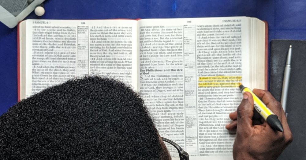 Highlighter - Man highlighting text while studying with a book and tablet on a desk.