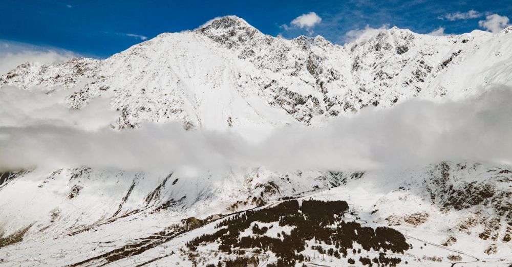 Altitude Sickness - A breathtaking view of a snow-covered mountain range under a clear blue sky.