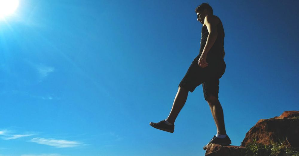 Solo Climbers - Man on a cliff's edge enjoying a bright sunny day outdoors.