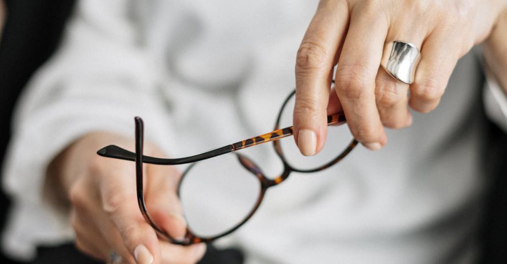 Expert Climbers - Close-up of a woman holding glasses, symbolizing thought and professionalism.