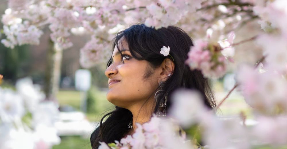 BC Gardens - A woman in a black sari enjoys cherry blossoms in springtime Vancouver park.