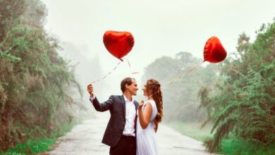 Couple Gardens - A loving couple embraces with heart-shaped balloons in a foggy park setting.