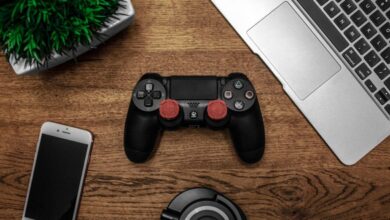 Gadgets - A flat lay photo showcasing a gaming console, laptop, smartphone, and headphones on a wooden tabletop.