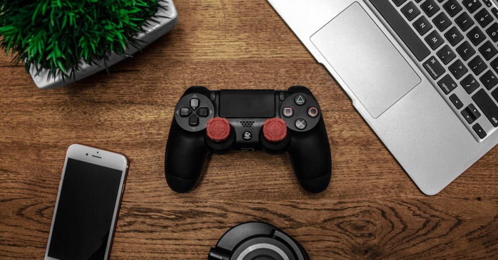 Gadgets - A flat lay photo showcasing a gaming console, laptop, smartphone, and headphones on a wooden tabletop.