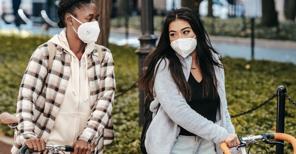 Best Time For Gardens - Multiethnic girlfriends in masks talking to each other while strolling with bicycles in park during COVID pandemic