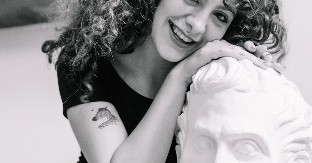 Top Museums - Smiling woman with curly hair affectionately poses with a bust in a creative studio.