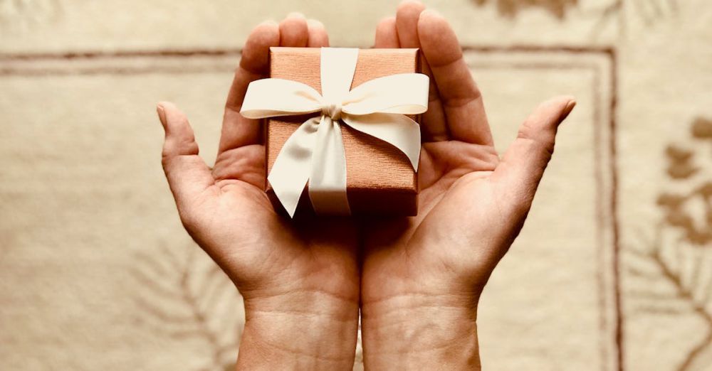 Gifts - Close-up of hands holding a beautifully wrapped gift box with a ribbon, perfect for celebrations and surprises.