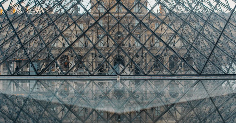 Popular Museums - The Louvre Pyramid reflecting in the water during a serene day in Paris. Iconic architecture at its finest.