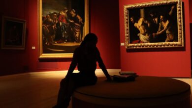 Museum Experience - Silhouetted visitor in an art gallery with dramatic lighting on classic paintings.