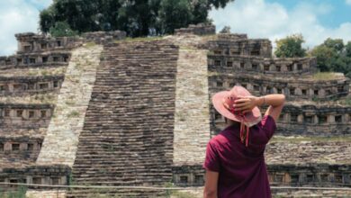 Indigenous History - A man in a hat admires the ancient pyramid in Cuetzalan, México under a bright summer sky.