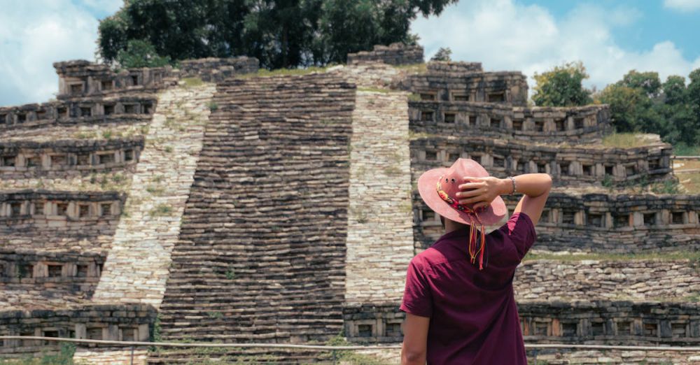 Indigenous History - A man in a hat admires the ancient pyramid in Cuetzalan, México under a bright summer sky.