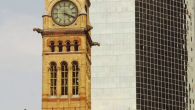 Canadian History - Old City Hall clock tower alongside modern skyscraper in Toronto, blending historic and contemporary architecture.