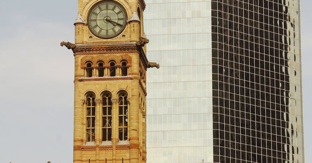 Canadian History - Old City Hall clock tower alongside modern skyscraper in Toronto, blending historic and contemporary architecture.