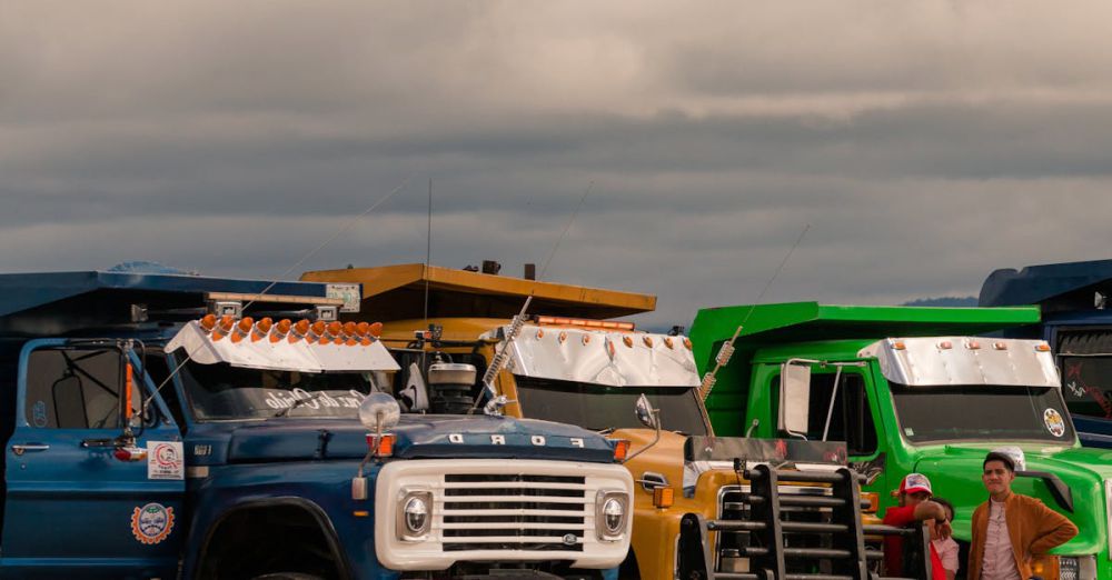 Family Road Trips - A row of vibrant trucks lined up outdoors with a family nearby under an overcast sky.