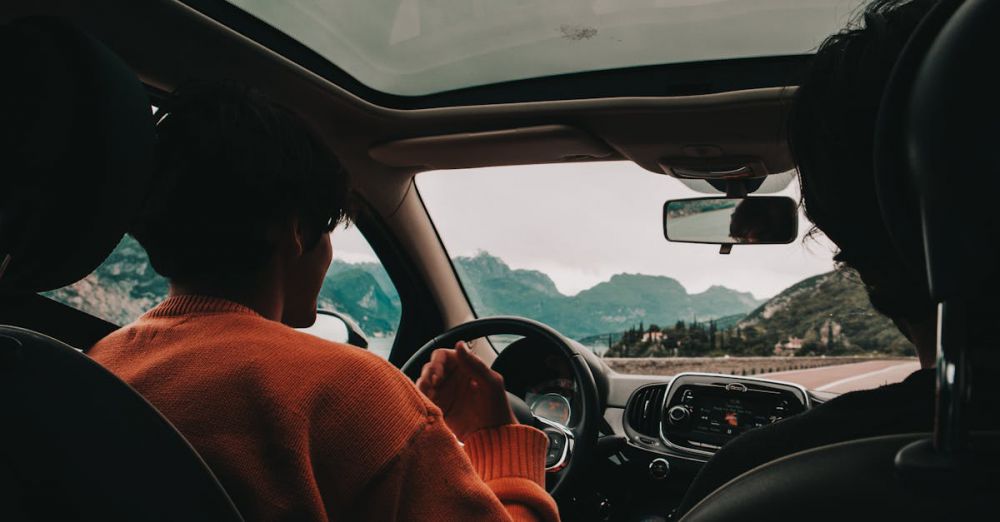 Cross-Country Trip - Enjoy a scenic drive through mountains with friends. Front passenger view from inside the car.