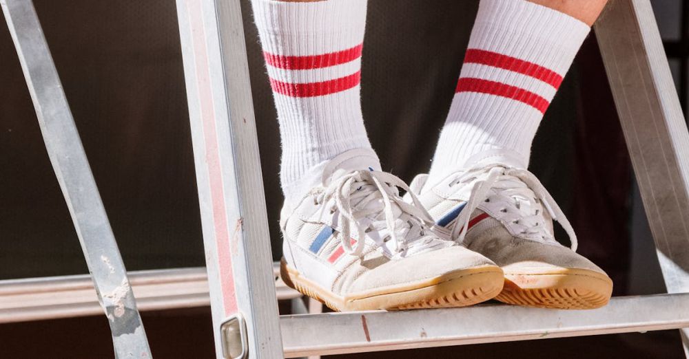 Shoes - Close-up of sneakers and socks on a metal ladder in bright sunlight, emphasizing casual style.