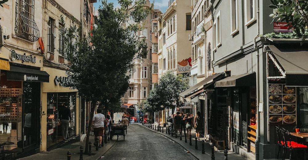 History Road Trips - Narrow cobblestone street with old buildings and lush summer greenery in bright day