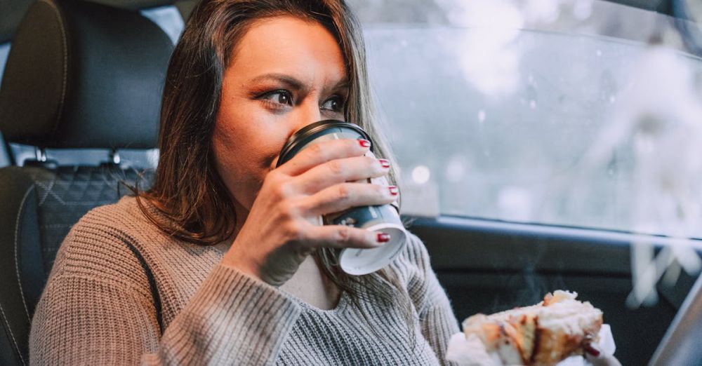 Foodie Road Trips - Woman enjoying coffee and pastry inside a car, reflecting a cozy morning routine.