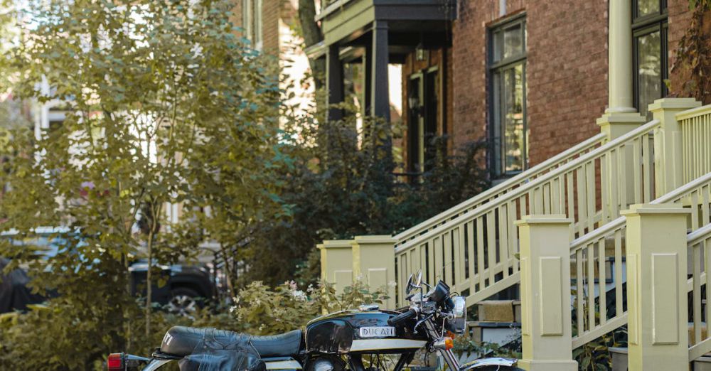 Quebec Road Trips - Classic black motorcycle parked outside townhouses in a leafy Québec street, capturing a nostalgic vibe.