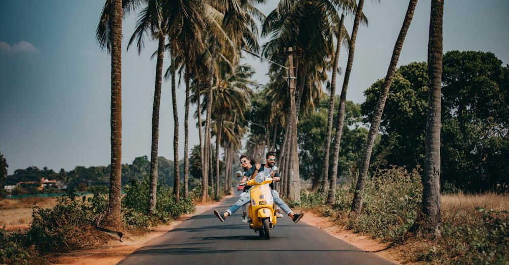 Couple Road Trips - A joyful couple rides a yellow scooter through a scenic palm-lined road, capturing the essence of tropical travel and adventure.