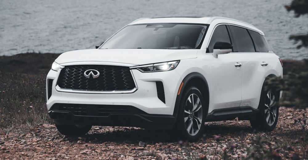 Road Trip Vehicle - A white luxury SUV parked on a rocky coast with an ocean backdrop, showcasing elegance and adventure.