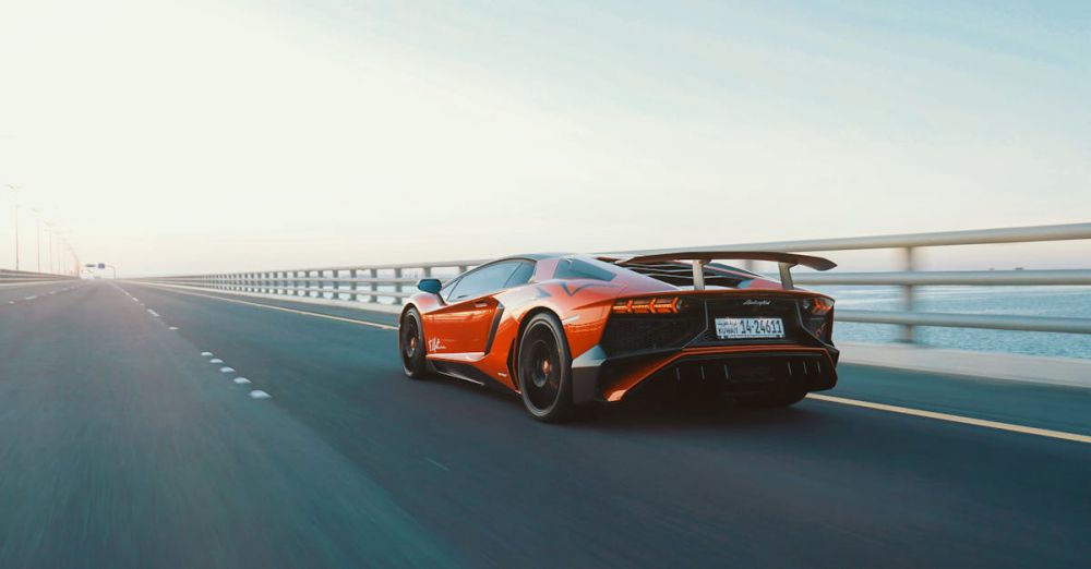 Coastal Road Trips - Dynamic shot of a red sports car speeding on an open coastal highway during the day.