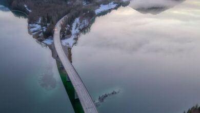 Mountain Road Trips - A stunning aerial view of a bridge over a lake surrounded by Alps in Bavaria, Germany.