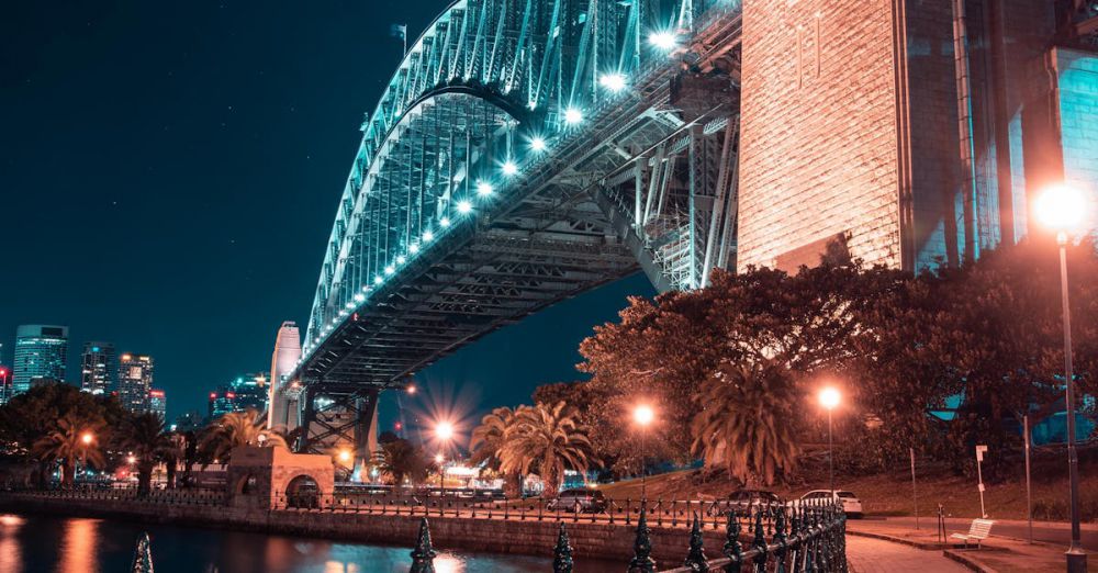 Night Photography - A stunning night view of Sydney Harbour Bridge with glowing lights and water reflections.