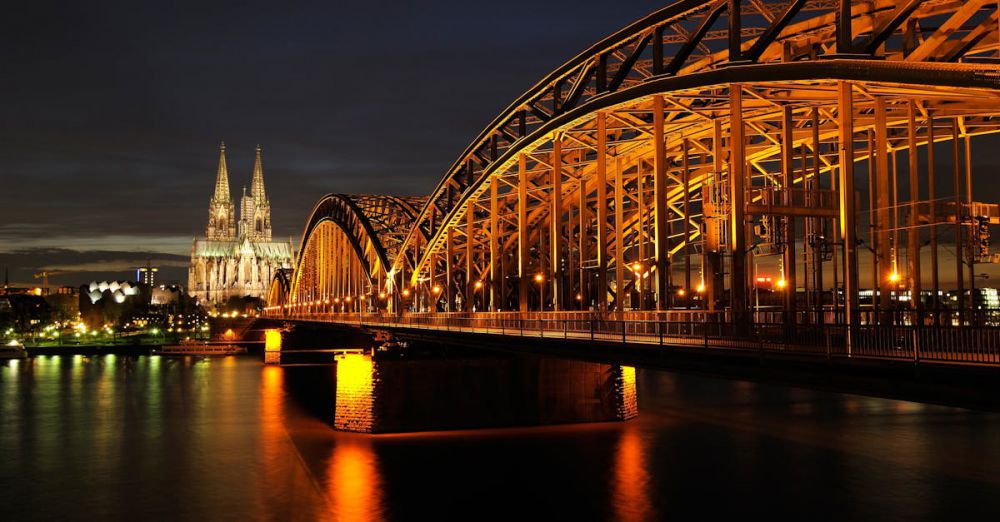 Cologne - Captivating night shot of Cologne Cathedral and Hohenzollern Bridge reflected on the Rhine River.